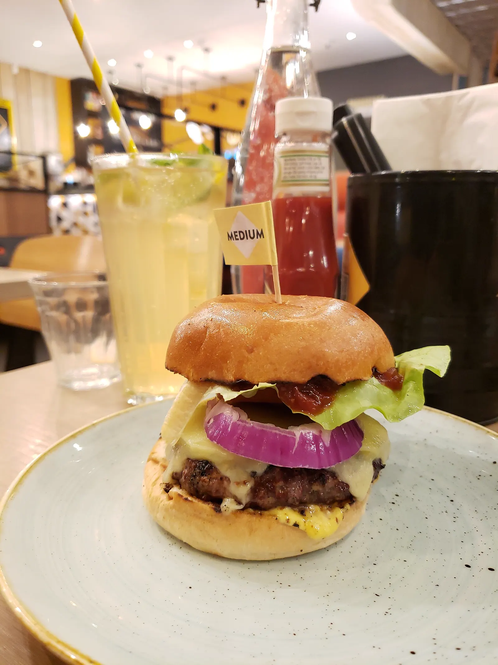 Hambúrguer alto com bacon, cebola roxa e queijo derretendo