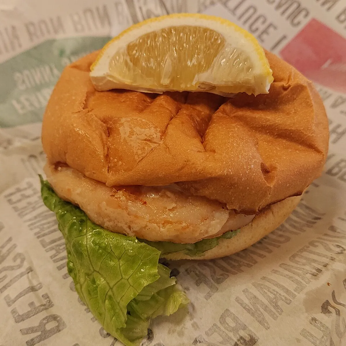 Burger de camarão empanado com alface e uma fatia de limão